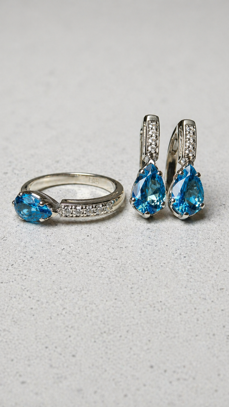 Premium Jewelry - pierścionek i kolczyki z niebieskim topazem na betonie